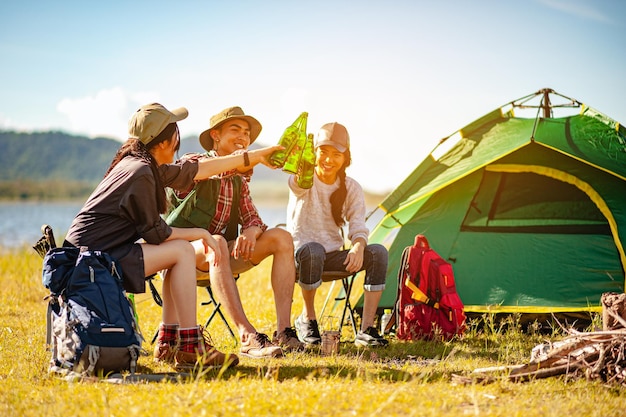 Equipe de alpinistas asiáticos alpinistas está sentado e desfrutando de uma bebida depois de montar uma barraca ao ar livre na temporada de outono de caminho de floresta. Caminhadas, alpinista, equipe, floresta, camping, conceito de atividade.