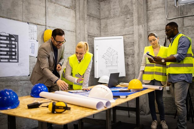 Foto equipe de arquitetos e engenheiros experientes analisando o plano de construção no canteiro de obras