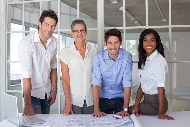 Equipe de arquitetos passando por planos, sorrindo na câmera