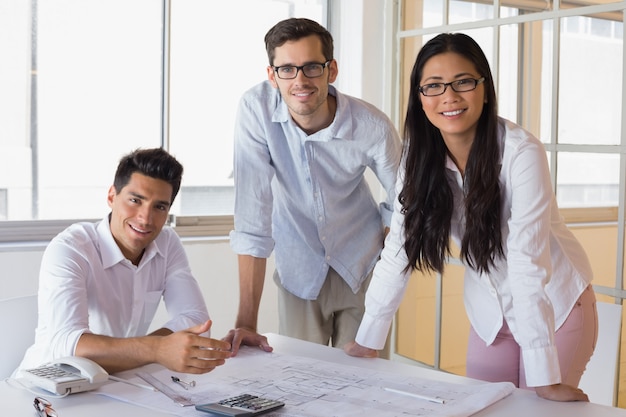 Equipe de arquitetura casual trabalhando juntos, sorrindo para a câmera