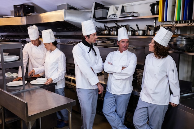 Equipe de chefs de pé juntos na cozinha comercial