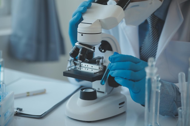 Equipe de cientistas de pesquisa bioquímica trabalhando com microscópio para desenvolvimento de vacina contra coronavírus em foco seletivo de laboratório de pesquisa farmacêutica