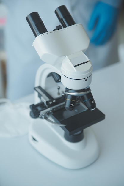 Equipe de cientistas de pesquisa bioquímica trabalhando com microscópio para desenvolvimento de vacina contra coronavírus em foco seletivo de laboratório de pesquisa farmacêutica