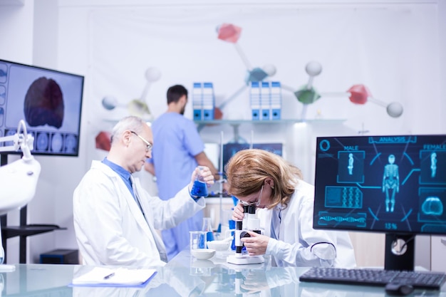 Equipe de cientistas trabalhando juntos em um laboratório. Químico sênior com tubo de ensaio na mão.