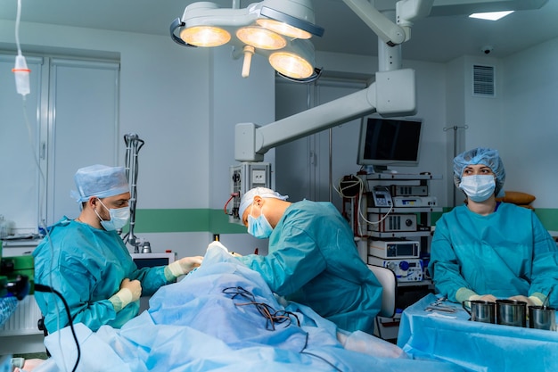 Equipe de cirurgiões operando equipamentos modernos na sala de cirurgia