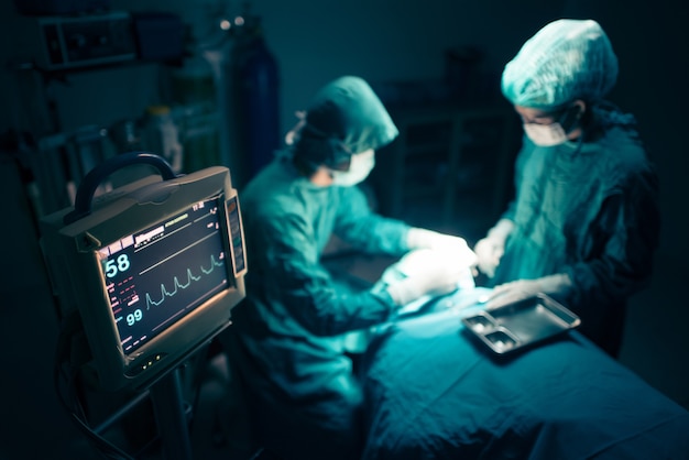 Equipe de cirurgiões trabalhando com monitoramento em sala cirúrgica.