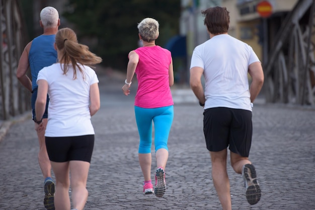 equipe de corredores de jogging em grupo de pessoas no treino matinal com o nascer do sol ao fundo