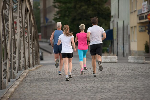 equipe de corredores de jogging em grupo de pessoas no treino matinal com o nascer do sol ao fundo