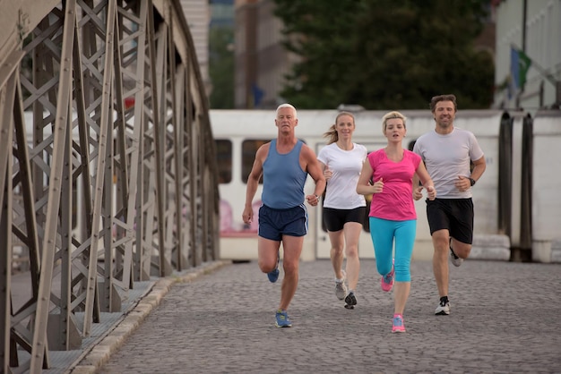 equipe de corredores de jogging em grupo de pessoas no treino matinal com o nascer do sol ao fundo