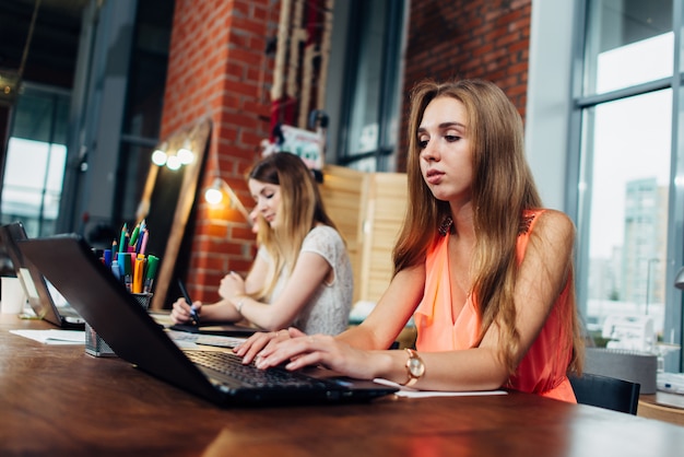 Equipe de designers de interiores femininos usando laptops e amostras de cores durante o processo de trabalho no escritório elegante