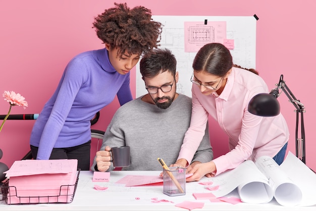 Equipe de diversas mulheres e colegas de trabalho qualificados compartilham ideias enquanto fazem projetos futuros focados em papéis posam juntos na mesa cooperam para tarefas comuns têm olhares atentos. Conceito de trabalho em equipe