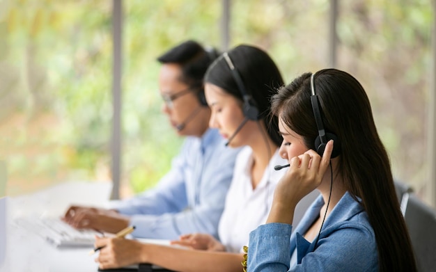 Equipe de diversos operadores de linha direta com fones de ouvido prestando atendimento aos clientes no call center