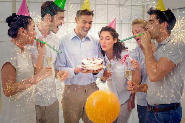 Equipe de empresários casuais comemorando um aniversário contra fogos de artifício coloridos explodindo em fundo preto