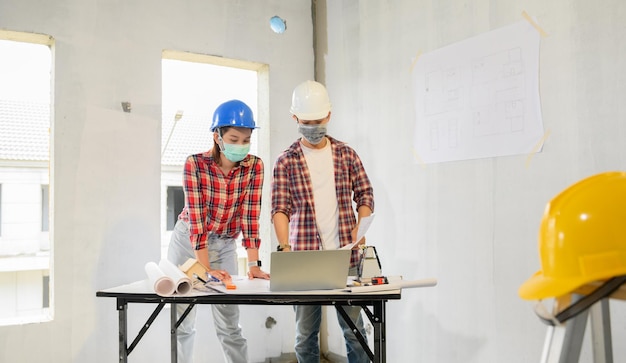 Equipe de engenheiros discute e trabalha no canteiro de obras. Inspeção no projeto da vila e na construção da propriedade.