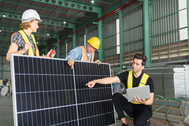 Equipe de engenheiros e técnicos trabalhando juntos em um painel solar em uma fábrica