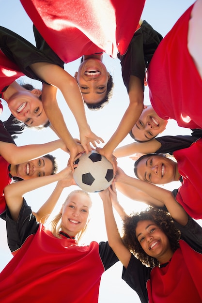 Equipe de futebol com bola formando amontoados contra o céu