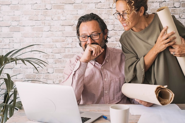 Equipe de homens e mulheres trabalhando felizes juntos na mesa olhando a tela do computador Trabalhadores profissionais gostam de trabalho e atividade de negócios Casal apreciado usando laptop e tecnologia para trabalhar moderno