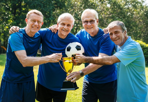 Equipe de jogadores de futebol maduros, vencendo a taça