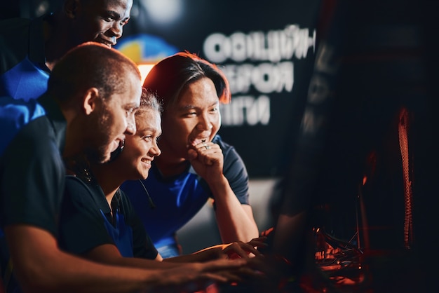 Foto equipe de jogadores profissionais de esportes cibernéticos felizes olhando para a tela do computador e se sentindo animados e felizes