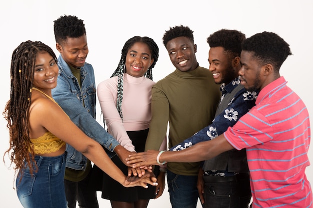 Foto equipe de jovens bonitos em uma parede branca de mãos dadas