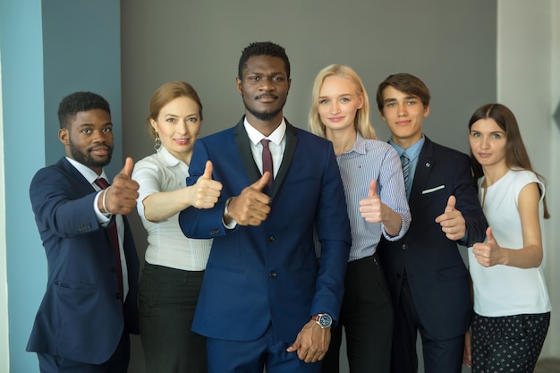 equipe de jovens bonitos no escritório com gesto de mão