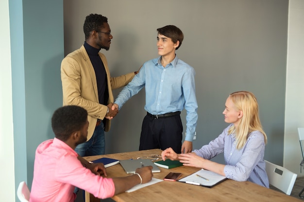 Equipe de jovens bonitos no escritório com um aperto de mão