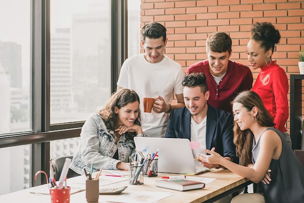 Equipe de jovens designers, observando seu projeto de colega de trabalho em um escritório.