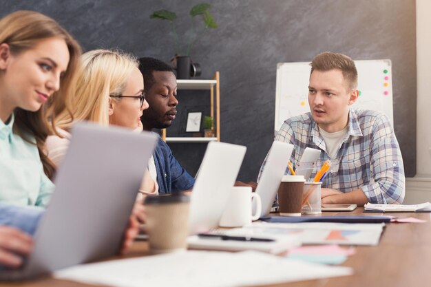 Equipe de jovens programadores com líder de equipe trabalhando em empresa de desenvolvimento de software, discutindo novo projeto, copie espaço