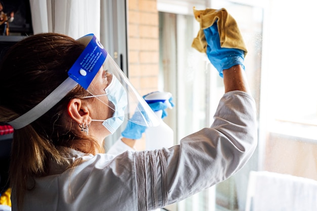 Foto equipe de limpeza desinfetando a casa contra vírus, usando máscara protetora transparente