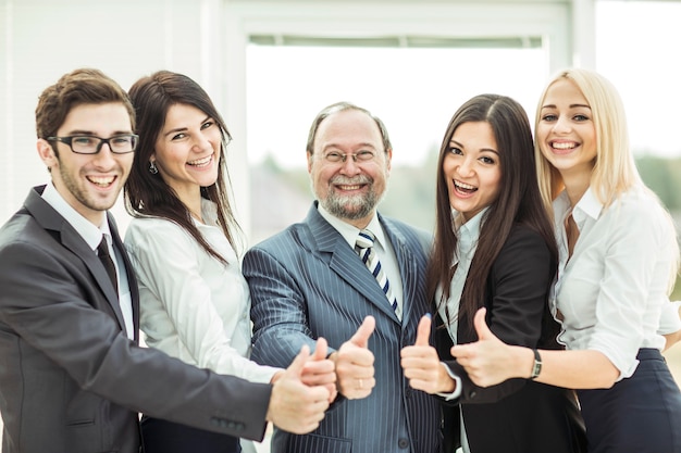 Equipe de negócios amigável para a vitória fazendo um gesto de polegar para cima