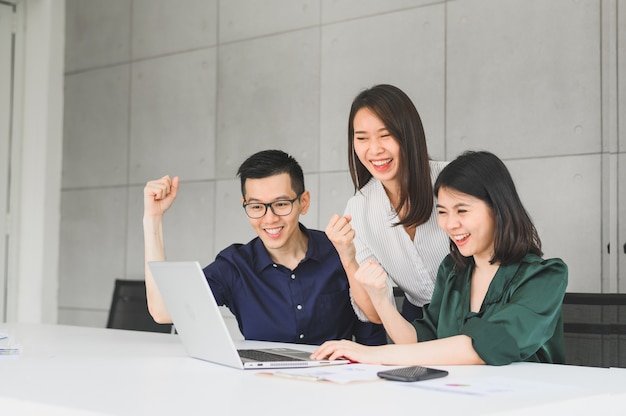 Equipe de negócios asiáticos entusiasmada e feliz levantando o braço para celebrar o sucesso