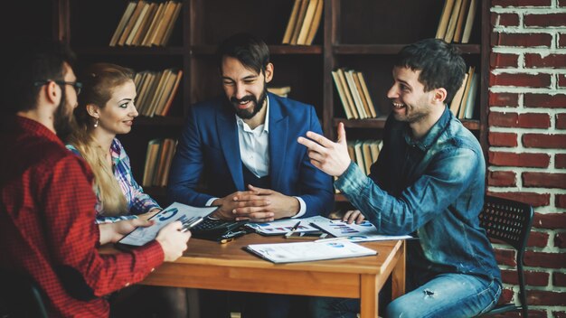 Equipe de negócios bem-sucedida discutindo um relatório financeiro sobre os lucros da empresa no local de trabalho no escritório