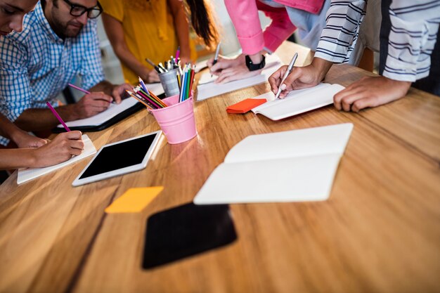 Equipe de negócios casuais, escrevendo em cadernos