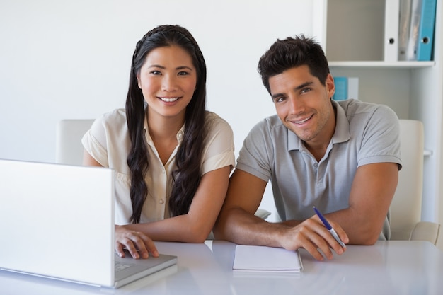 Equipe de negócios casuais usando laptop juntos na mesa