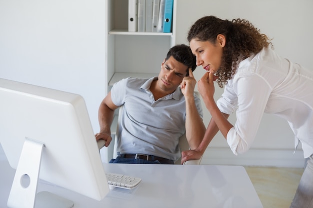 Equipe de negócios casual olhando computador juntos na mesa