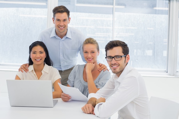 Equipe de negócios casual trabalhando juntos na mesa, sorrindo para a câmera