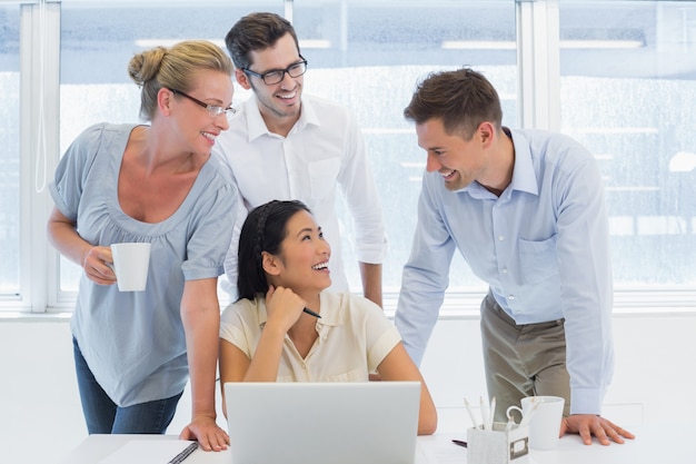 Equipe de negócios casual usando laptop juntos e sorrindo