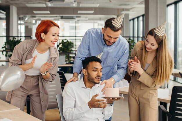 Equipe de negócios comemorando o aniversário do colega no moderno officexA