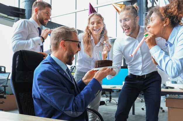 Equipe de negócios comemorando um aniversário de colega no escritório moderno