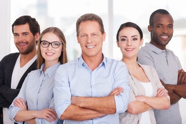 Foto equipe de negócios confiante. grupo de alegres executivos em roupas casuais, próximos uns dos outros e de braços cruzados