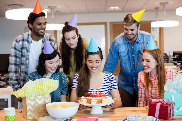 Equipe de negócios criativos comemorando aniversário de colegas no escritório