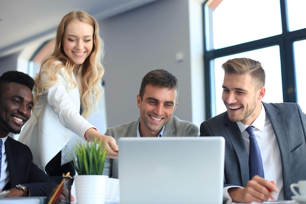 Equipe de negócios de inicialização em reunião em um moderno e brilhante escritório interior de brainstorming, trabalhando em um laptop e tablet.