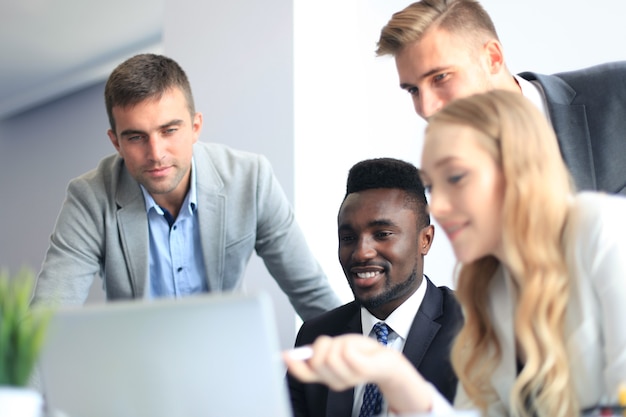 Equipe de negócios de inicialização em reunião em um moderno escritório brilhante interior de brainstorming, trabalhando em um laptop e tablet.