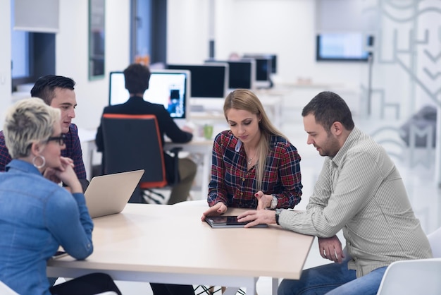 Equipe de negócios de inicialização em reunião em um moderno escritório brilhante interior de brainstorming, trabalhando em um laptop e tablet.