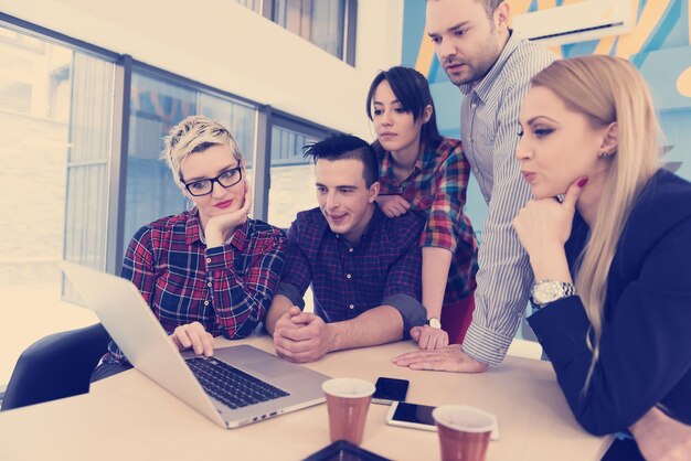 Equipe de negócios de inicialização em reunião em um moderno escritório brilhante interior de brainstorming, trabalhando em um laptop e tablet.