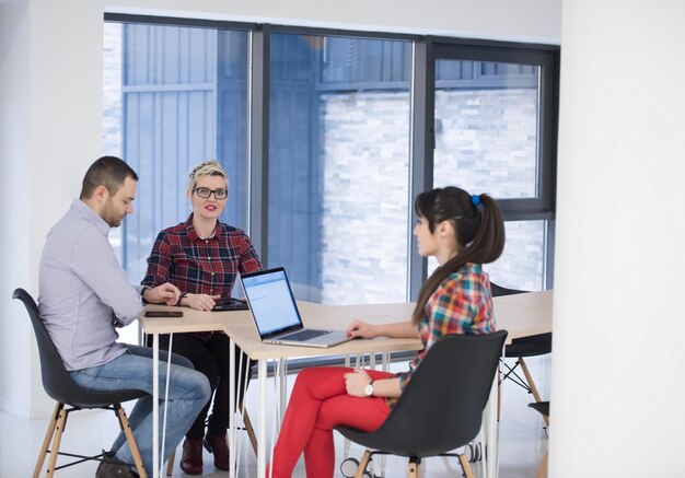 Equipe de negócios de inicialização em reunião em um moderno escritório brilhante interior de brainstorming, trabalhando em um laptop e tablet.