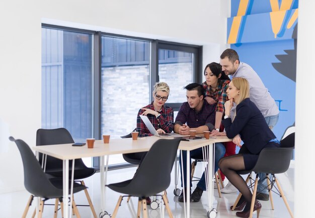 Equipe de negócios de inicialização em reunião em um moderno escritório brilhante interior de brainstorming, trabalhando em um laptop e tablet.