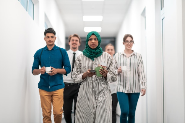 Equipe de negócios de inicialização multiétnica andando pelo corredor do prédio enquanto voltava de uma pausa para o café. Foto de alta qualidade