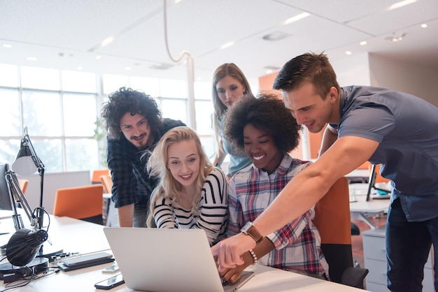 Equipe de negócios de inicialização multiétnica em reunião no interior do escritório brilhante moderno brainstorming, trabalhando no laptop