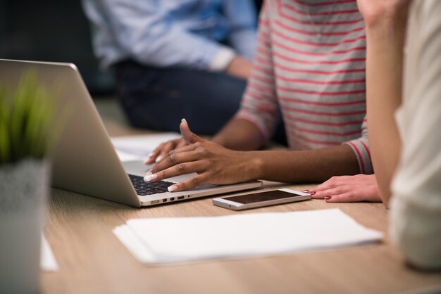 Equipe de negócios de inicialização multiétnica em reunião no interior do escritório noturno moderno brainstorming, trabalhando no laptop